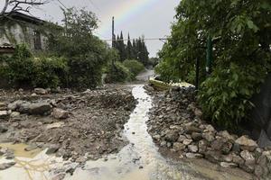 Mud stream of water and mudflows flowing along the road, demolished, damaged, flooded cars and houses on a rainbow background. Natural disaster insurance concept. photo