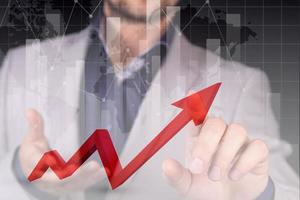 Stock market growth graph, manipulations with forex, the hand of a businessman indicates a red graph of growth and profit, a red danger zone against the background of the world map. Double exposure. photo