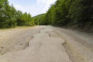 After an earthquake and a strong storm, the remains of an asphalt road in the mountains. Closed road. Destroyed asphalt road. Broken asphalt, crack and landslides. photo