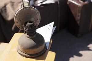 Dusty, antique, kerosene lamp against the background of an old suitcase. photo