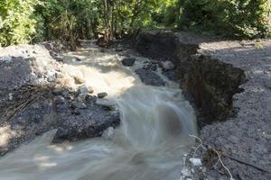 corriente sucia de un río de montaña después de la lluvia y el flujo de lodo con erosión del suelo. concepto de deslizamientos de tierra y desastres naturales foto