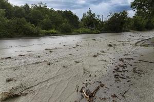 una carretera destruida después de una inundación y un flujo de lodo con agua sucia que fluye. concepto de desastres naturales. foto