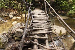 Wooden flooring of a dilapidated bridge over a mountain river on an ecological trail in a summer mountain forest. photo