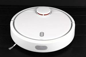 Modern white robotic, vacuum cleaner, isolated on black background. photo