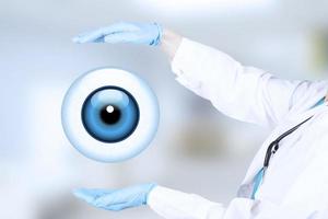 Realistic human eye with blue cornea as a round icon with protective hand gesture, female ophthalmologist, wearing white medical clothes. Blue medical blurred background. photo