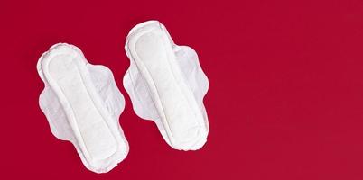 Two feminine sanitary pads, napkins. Feminine hygiene products during the menstrual cycle. Red background. Copy space. photo
