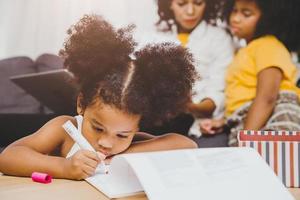 los niños negros americanos de la hija del preescolar hacen los deberes aprendiendo educación con su hermana viviendo juntos en casa. foto