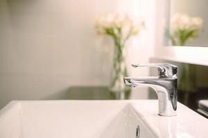 cuarto de baño interior lavabo de lujo y grifo en el inodoro para lavarse las manos con decoración floral foto