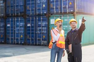 logistic worker man and woman working team with radio control loading containers at port cargo to trucks for export and import goods. photo