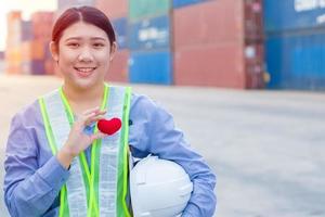 chica adolescente trabajadora en el puerto de envío de contenedores de carga trabajando con corazón y buen concepto de mente de servicio. foto