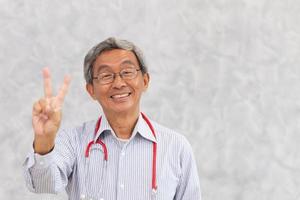 retrato de un médico chino anciano sano anciano asiático de pie sonrisa mano signo de victoria con espacio para texto. foto