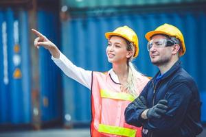 logistic worker man and woman working team with radio control loading containers at port cargo to trucks for export and import goods. photo