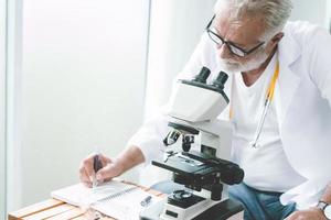 médico científico profesional que trabaja en la investigación de nuevas vacunas y virus y escribe un informe de notas en el laboratorio del hospital. foto