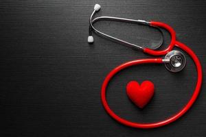Stethoscope doctor with red heart on black wooden table background with space for text. photo