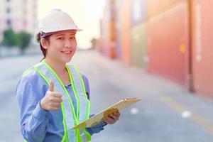 shipping worker show thumbs up sign for good work job done with shipyard import export cargo background. photo