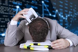 Crisis, sanctions, default. a businessman lies on a pile of papers, holding a hole punch against the background of a stock market growth and fall graph. photo