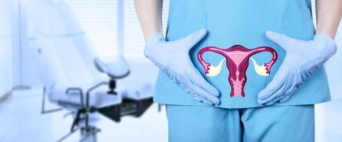 gynecologist and a model of the reproductive system of a woman, the uterus, at the level of the pelvic bones of a woman, on a blurred background of a gynecological chair in the office. photo