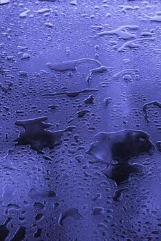 Close-up pattern with large water drops on a glass surface. Toned purple image in Very Peri trendy color. copy space. photo