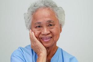 anciana asiática anciana paciente sentada y sonriente con cara feliz en la cama en el hospital. foto