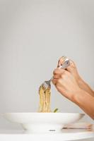 Hand holding fork and spoon eating spaghetti truffle cream sauce. photo