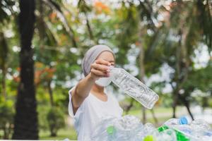 Woman hand holding recycle plastic bottle in garbage bin environment conceptual. photo