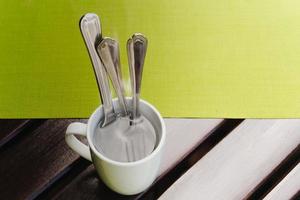 Health and hygiene soaking spoon and fork in hot water in cafe. photo