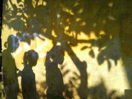 shadows of trees and small children on the walls of the house photo