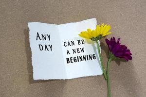 Motivational quote on torn white paper with sunflower on wooden table background. photo