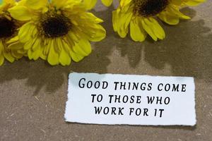 Motivational quote on torn white paper with sunflower on wooden table background photo