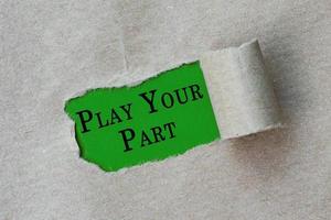 Play your part text on torn hole in the sheet of brown paper on green background photo
