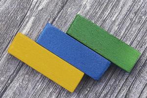 Three colorful wooden cubes against wooden background. Flat lay. Copy Space. photo