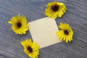 Torn brown paper on wooden surface and sunflower flat lay with copy space. photo