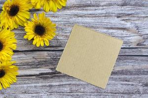 Torn brown paper on wooden surface and sunflower flat lay with copy space. photo