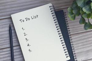 To do list text on notepad, pen and potted plant on wooden table. Flat lay. photo