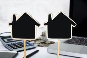 Wooden house model with blurred background of coins, calculator and notebook. photo