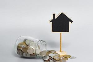 wooden house model with coins in a glass jar. Property investment concept. photo