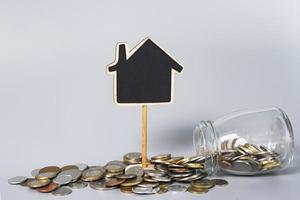 Wooden house model with coins in a glass jar. Property investment concept. photo