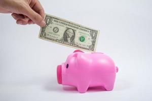 male hand putting coin into pink piggy bank photo