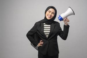 mujer musulmana feliz está anunciando con megáfono sobre fondo blanco foto