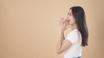 A Portrait of Asian woman with white T-shirt over Light brown background studio photo