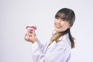 Una joven dentista sonriendo sobre un estudio de fondo blanco foto