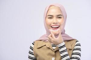 A young muslim woman holding invisalign braces in studio, dental healthcare and Orthodontic concept.. photo