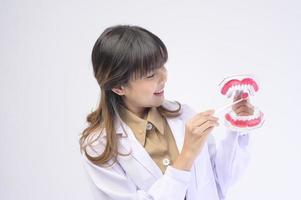 Una joven dentista sonriendo sobre un estudio de fondo blanco foto