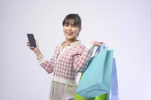 Shopper atractiva mujer sosteniendo bolsas de compras sobre fondo blanco. foto