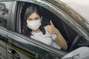 Young beautiful woman wearing a protective mask driving a car photo