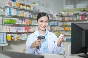 Farmacéutica femenina escaneando código de barras en una caja de medicamentos en una farmacia moderna. foto