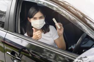 A woman holding atk in car, do a self-collection test for a COVID-19 test, health and safety photo