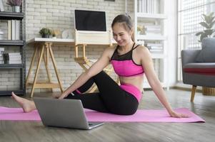 Fit young woman practicing yoga at home via online class with professional instructor, sport and healthy lifestyle concept. photo