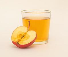 un vaso de jugo de manzana y medio de manzana roja aislado sobre fondo blanco. foto