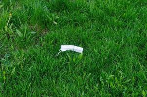 Discarded medical mask on grass. Environmental pollution after coronavirus pandemic. photo